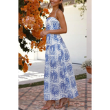 Woman showing side view  blue and white patterned empire waist maxi dress with spaghetti straps worn outdoors