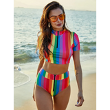 Beach Babes high waisted rainbow swimsuit with colorful vertical stripes worn by woman at the beach