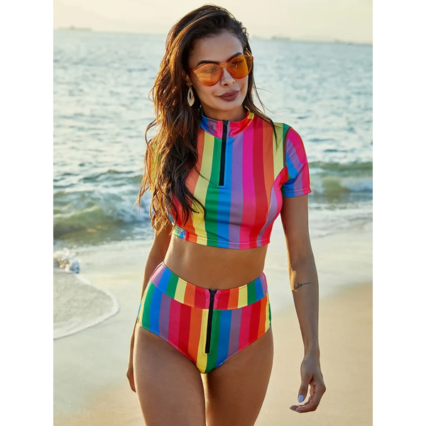Beach Babes high waisted rainbow swimsuit with colorful vertical stripes worn by woman at the beach