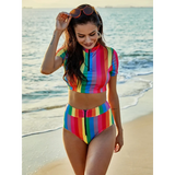 Beach Babes high waisted rainbow swimsuit with colorful vertical stripes and zip front on a beach