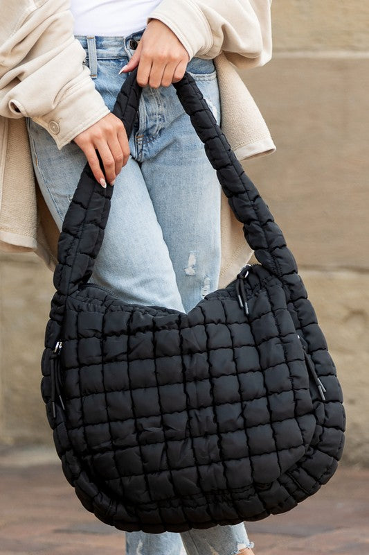 Lightweight Large Quilted Puffer Shoulder Bag in black held by person wearing jeans and beige jacket