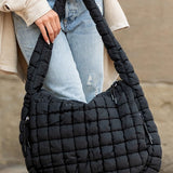 Lightweight Large Quilted Puffer Shoulder Bag in black held by person wearing jeans and beige jacket