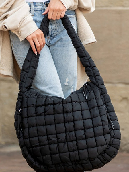 Lightweight Large Quilted Puffer Shoulder Bag in black held by person wearing jeans and beige jacket
