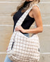 Lightweight Large Quilted Puffer Shoulder Bag in beige worn by woman with black top and jeans
