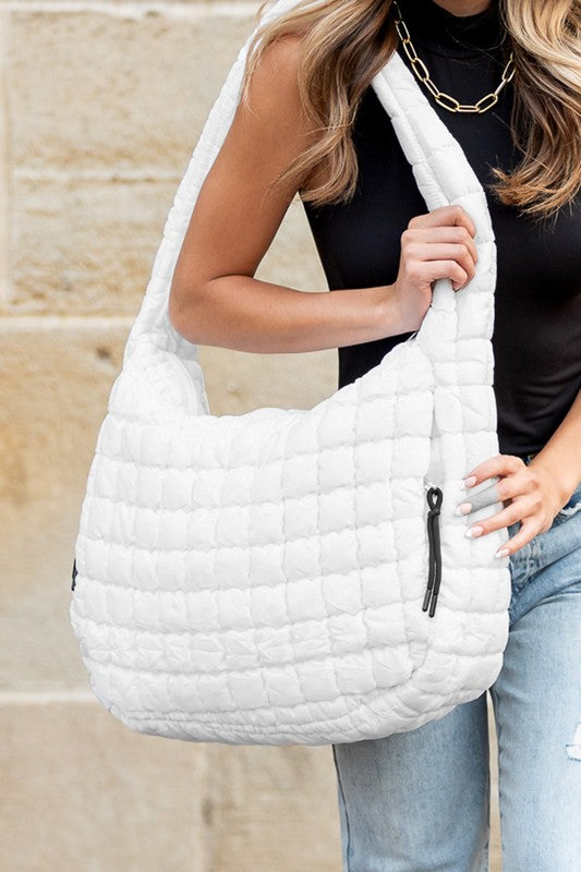 Lightweight Large Quilted Puffer Shoulder Bag in white carried by woman wearing black top and jeans