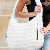 Lightweight Large Quilted Puffer Shoulder Bag in white carried by woman wearing black top and jeans