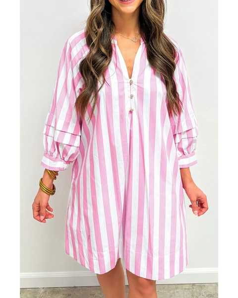 woman wearing a pink and white long sleeve vacation dress with vertical stripes and button detail