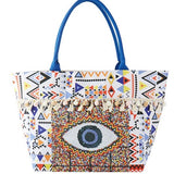 Babe Beachwear Pom Pom Evil Eye bag with colorful geometric patterns and blue handles