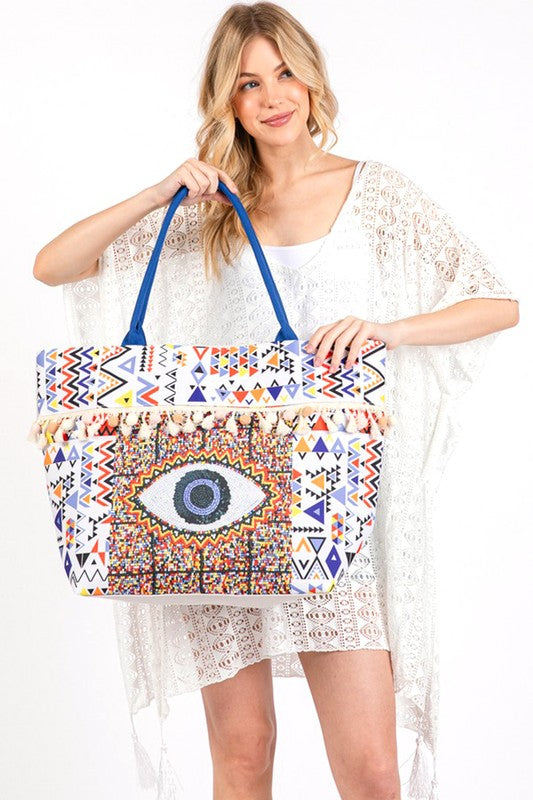 Pom Pom Evil Eye bag by Babe Beachwaer with colorful geometric patterns and blue handles