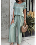 Light green satin pants set with short sleeve top and wide-leg pants accessorized with bracelets and a woven handbag