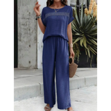 Woman wearing navy blue satin Pants Set with short sleeves and wide-leg pants holding a woven handbag