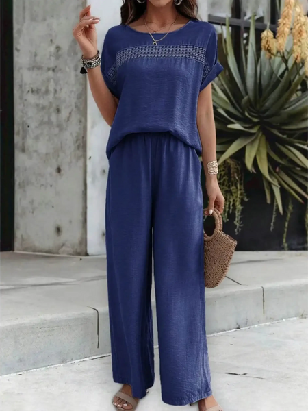 Woman wearing navy blue satin Pants Set with short sleeves and wide-leg pants holding a woven handbag