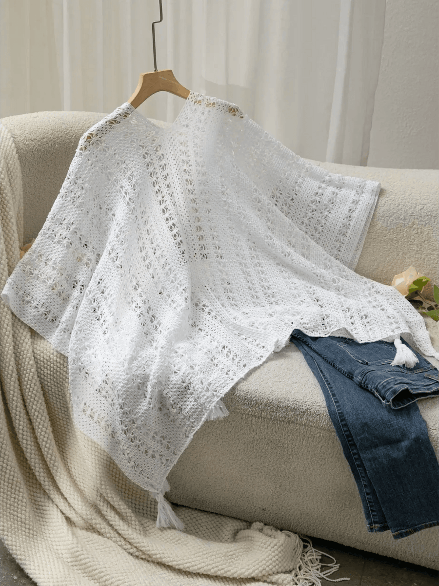 Trendsi white long sleeve shawl lightweight knit with tassels displayed on couch with jeans