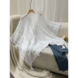 Trendsi white long sleeve shawl lightweight knit with tassels displayed on couch with jeans