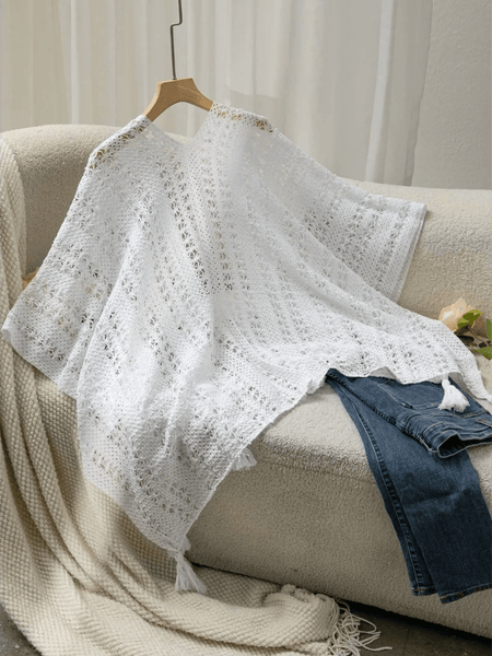 Trendsi white long sleeve shawl lightweight knit with tassels displayed on couch with jeans