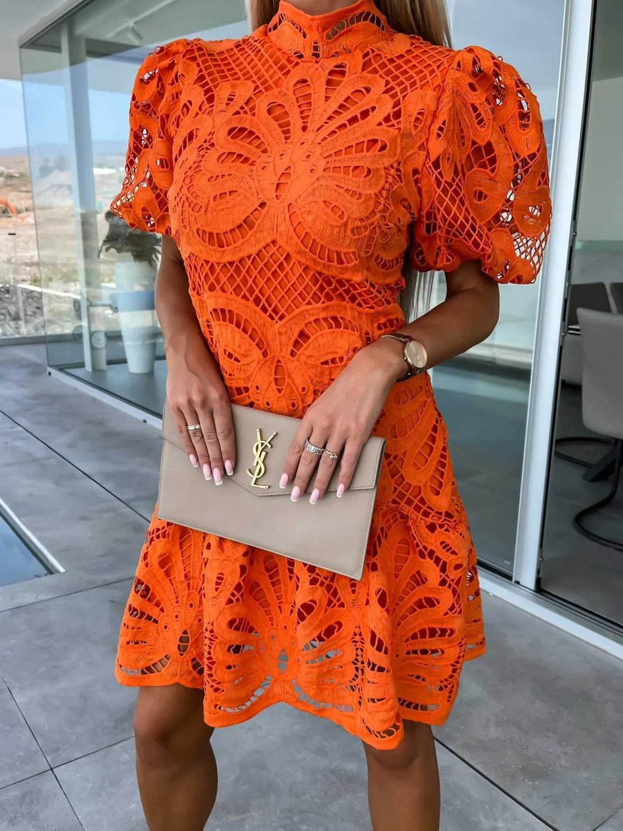 Trendsi orange midi dress with intricate cutout lace design and puff sleeves holding beige clutch