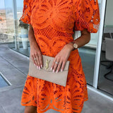Trendsi orange midi dress with intricate cutout lace design and puff sleeves holding beige clutch