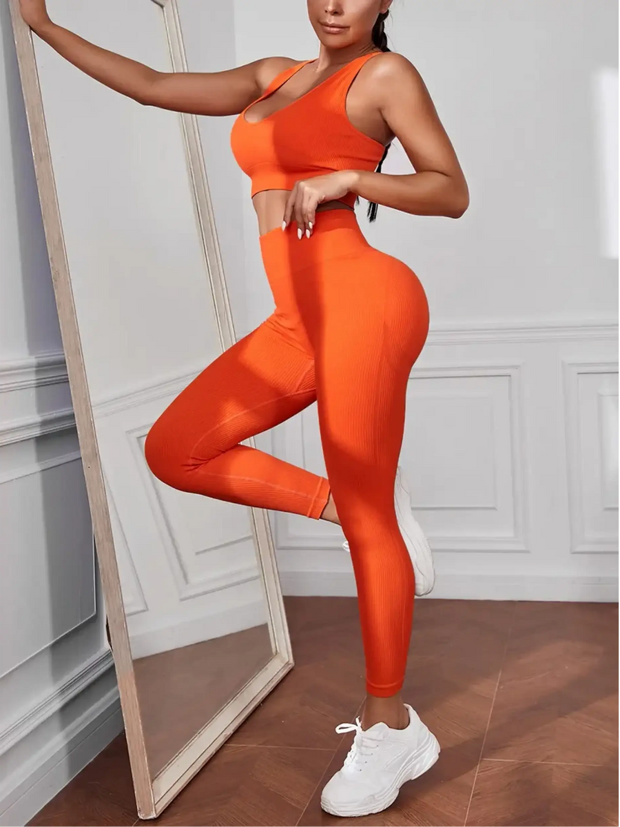 model wearing side view Trendsi women's compression leggings set in bright orange with matching sports bra and white sneakers