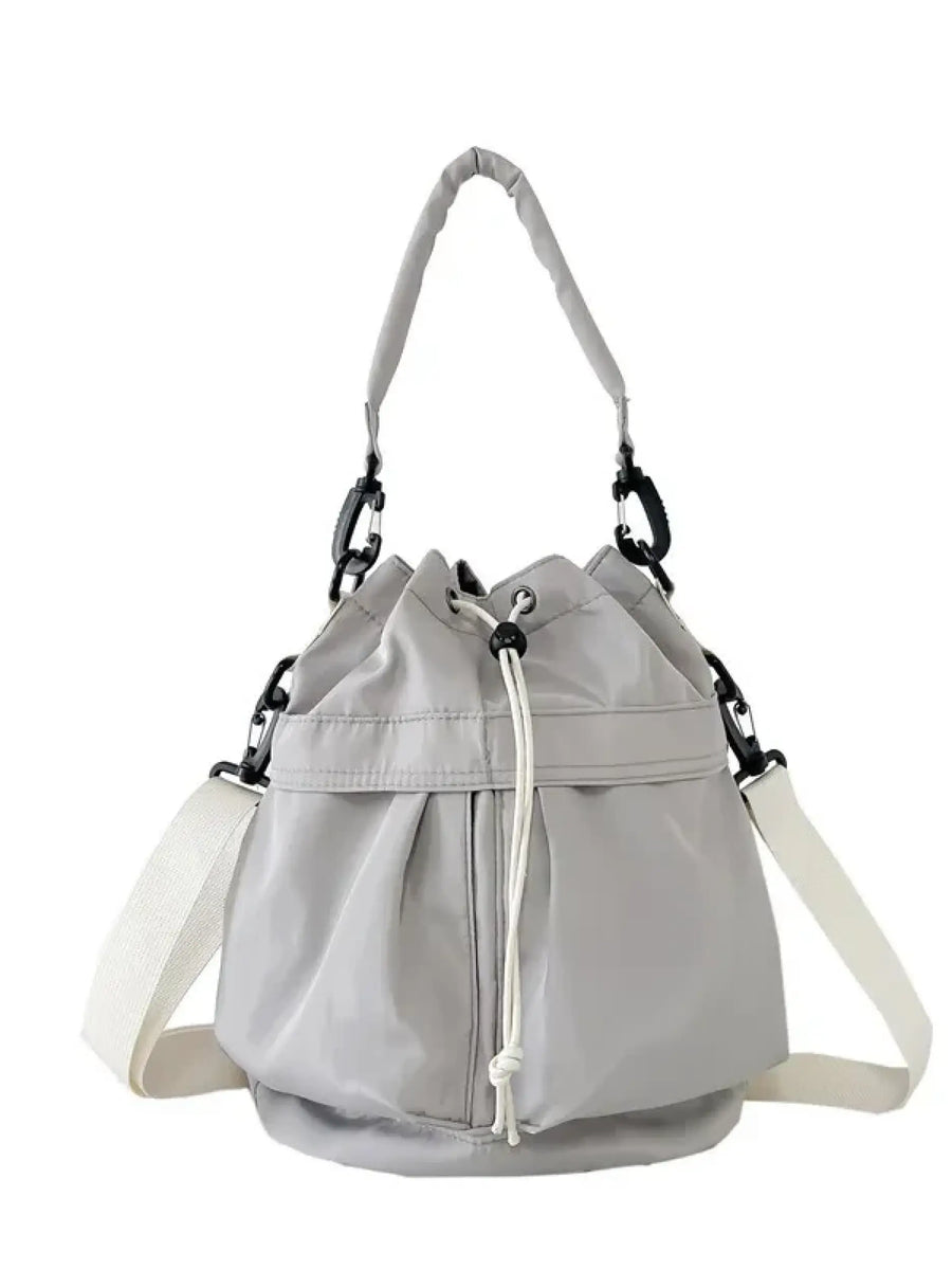 Light gray women's nylon bucket bag with adjustable white strap and drawstring closure