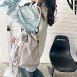 Trendsi women's nylon bucket bag in light beige worn on shoulder with adjustable strap