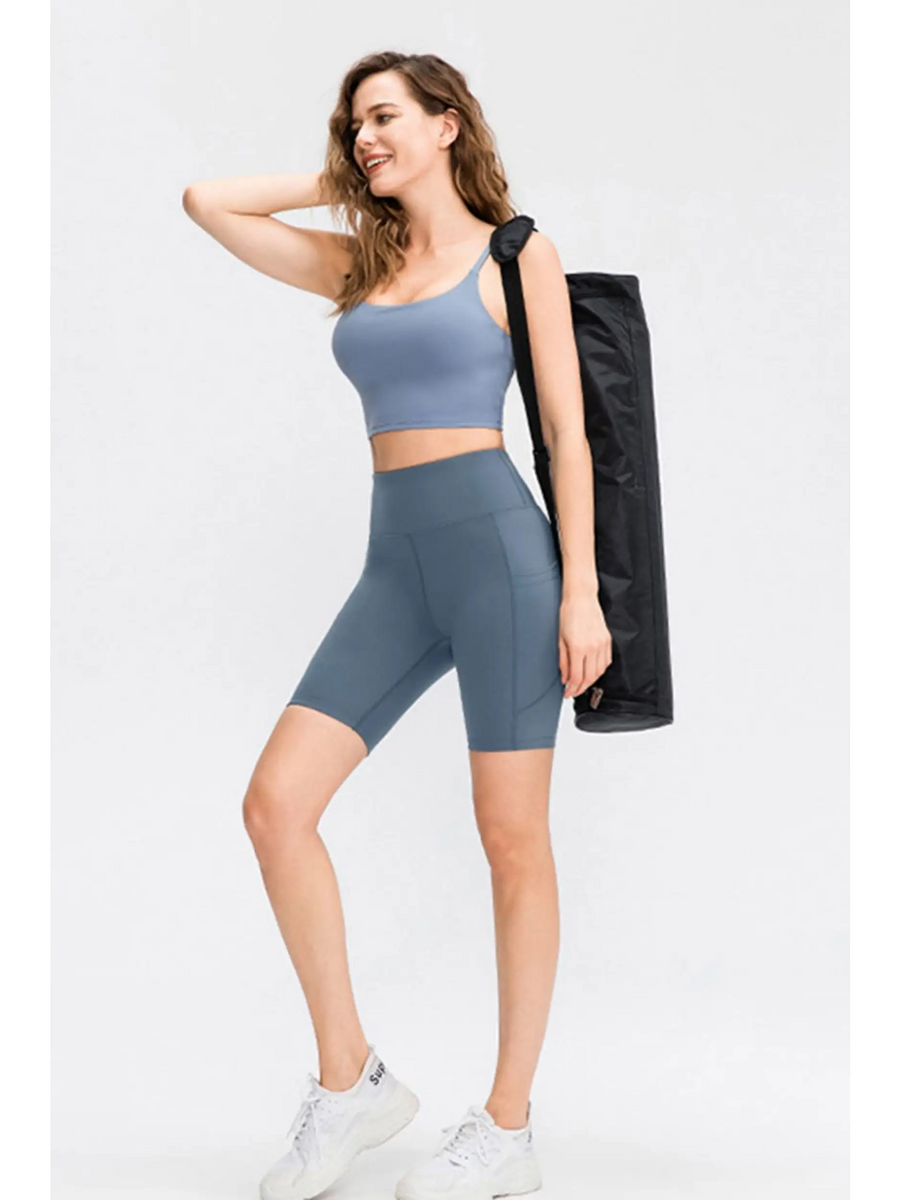 Woman wearing Babe Beachwear women's sports shorts with pockets in blue while carrying a yoga mat