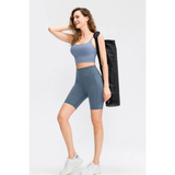 Woman wearing Babe Beachwear women's sports shorts with pockets in blue while carrying a yoga mat