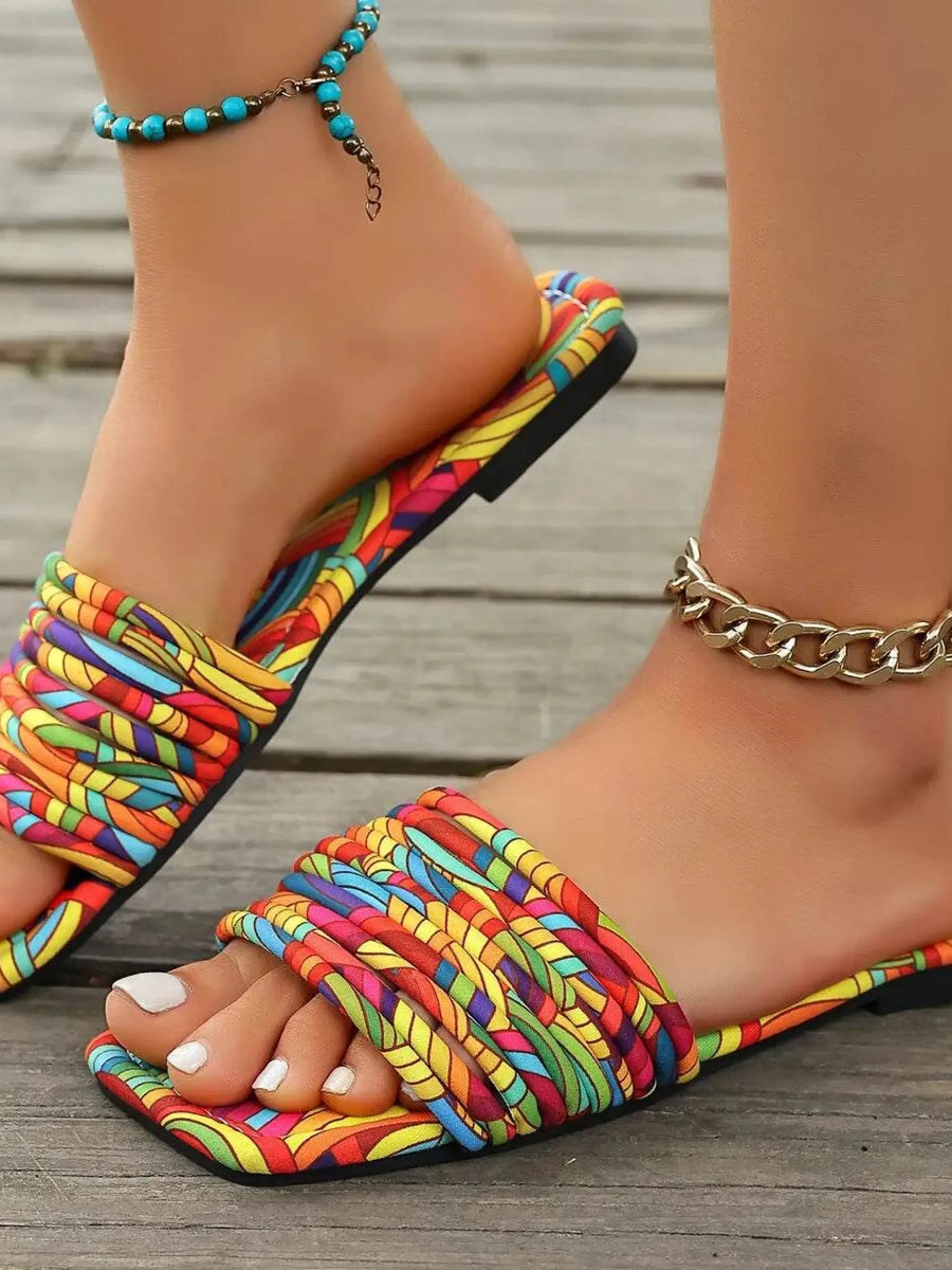 Babe Beachwear women's stylish slip on sandals with multicolor woven straps and flat sole on wooden floor