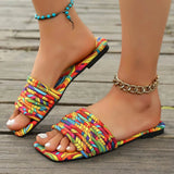 Babe Beachwear women's stylish slip on sandals with multicolor woven straps and flat sole on wooden floor