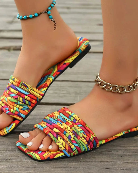 Babe Beachwear women's stylish slip on sandals with multicolor woven straps and flat sole on wooden floor