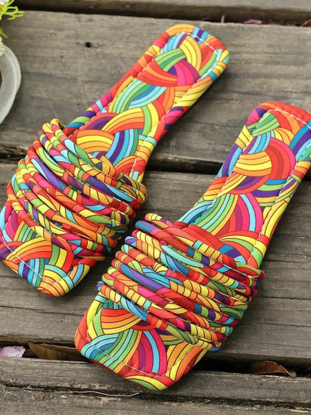 Babe Beachwear women's stylish slip on sandals with colorful rainbow braided straps on wooden surface