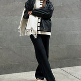 Rag Company women's suede loafers in beige worn with black pants and black jacket against gray wall