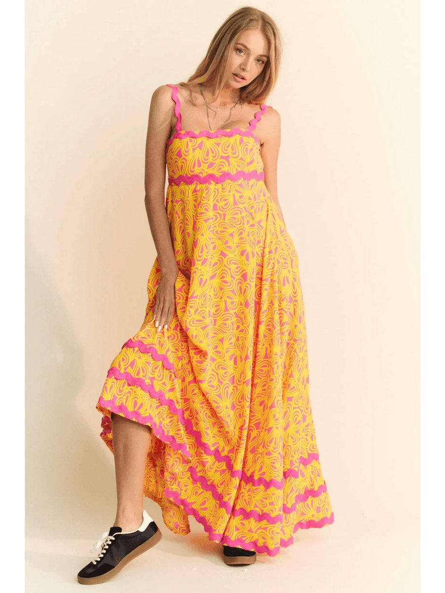 yellow floral sundress for travel with pink accents worn by woman in black sneakers