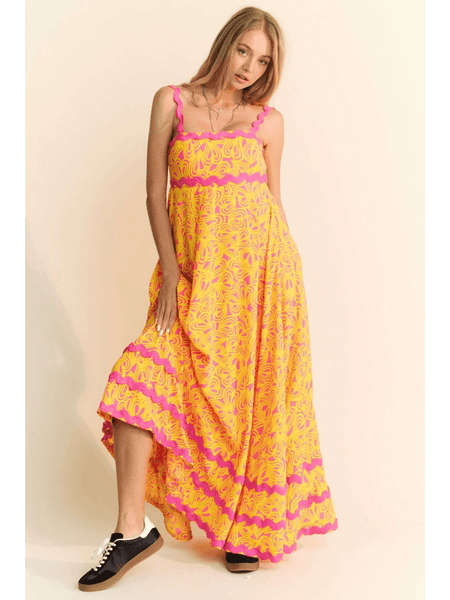 yellow floral sundress for travel with pink accents worn by woman in black sneakers