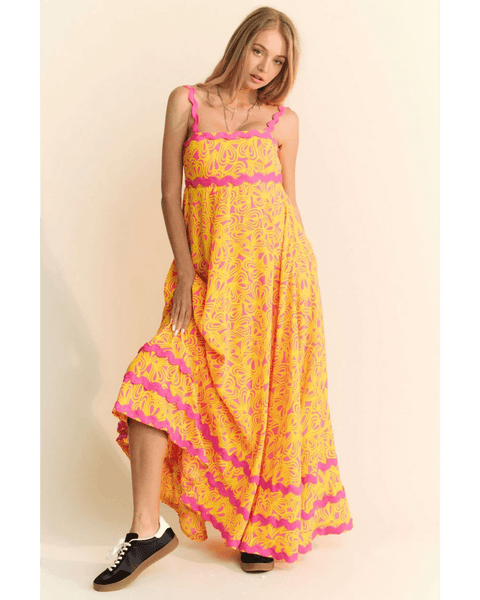 yellow floral sundress for travel with pink accents worn by woman in black sneakers