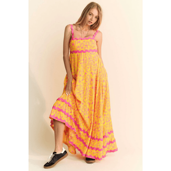 yellow floral sundress for travel with pink accents worn by woman in black sneakers
