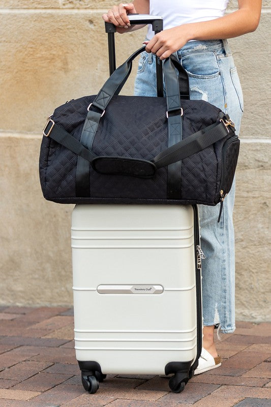 Zahra carry on overnight bag in black by Babe Beachwear placed on white rolling suitcase